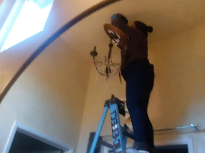 Electrician installing a chandelier in a Pemberton residence